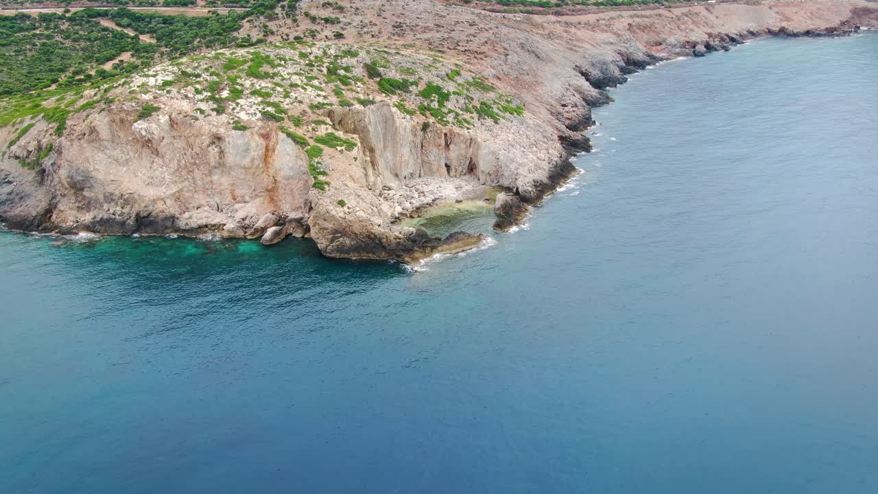Aerial panning shot of rugged coast and protected lagoon near Island of Crete