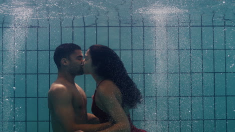 playful couple kissing underwater in swimming pool young people enjoy romantic kiss passionate lovers submerged in water floating with bubbles enjoying romance