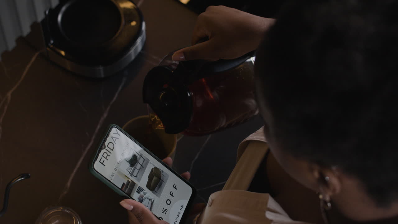 Person pouring a drink and looking at an advertisement on a mobile phone
