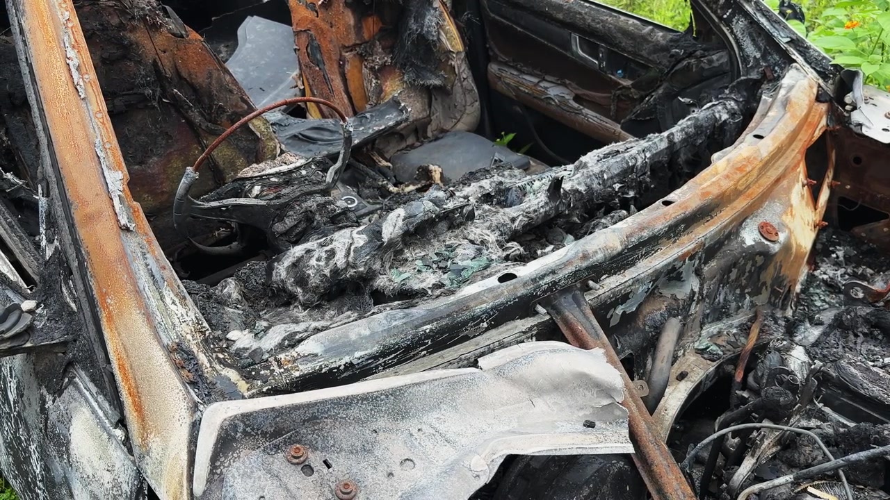 Tracking shot showing the burned front seat and charred steering wheel of a severely fire damaged car