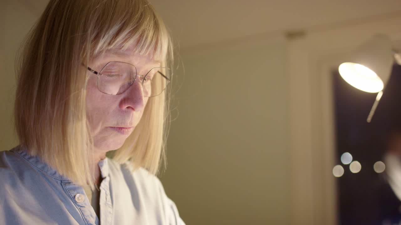 Mature woman in her 60s working from home online late at night