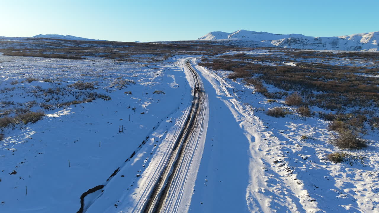 Aerial shot of Provincial Route 26 leading to Caviahue, Argentina, flanked by snow-covered landscapes and the Andes mountain peaks, gateway to volcanic and Araucaria forest scenery