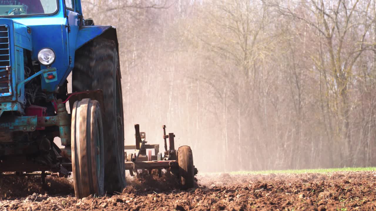 granjero conduce un viejo tractor soviético y cultiva un campo agrícola polvoriento