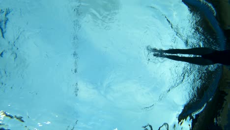 underwater shot looking up at a swimmer in a swimming pool using the butterfly stroke
