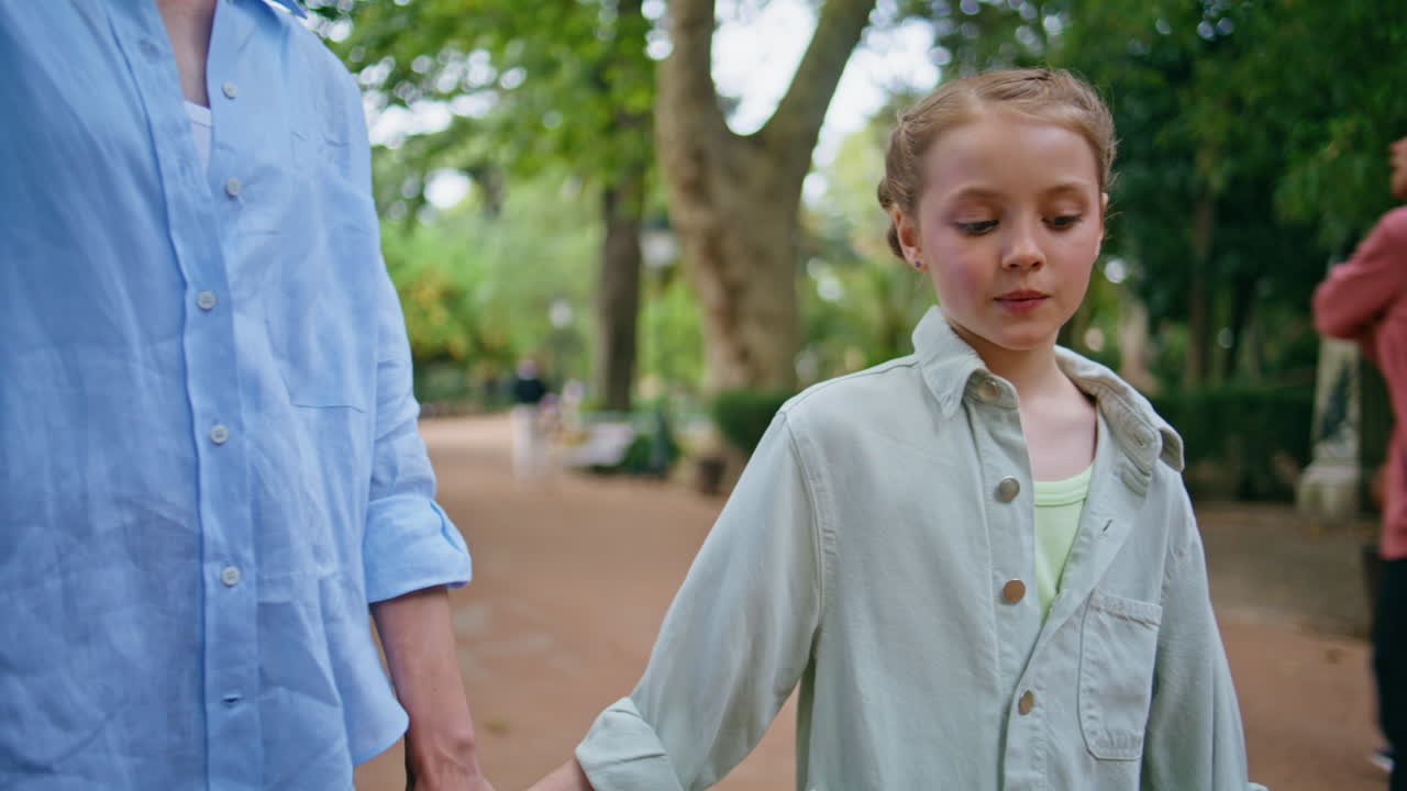Funny child strolling park talking mommy closeup. Lovely blonde kid walking