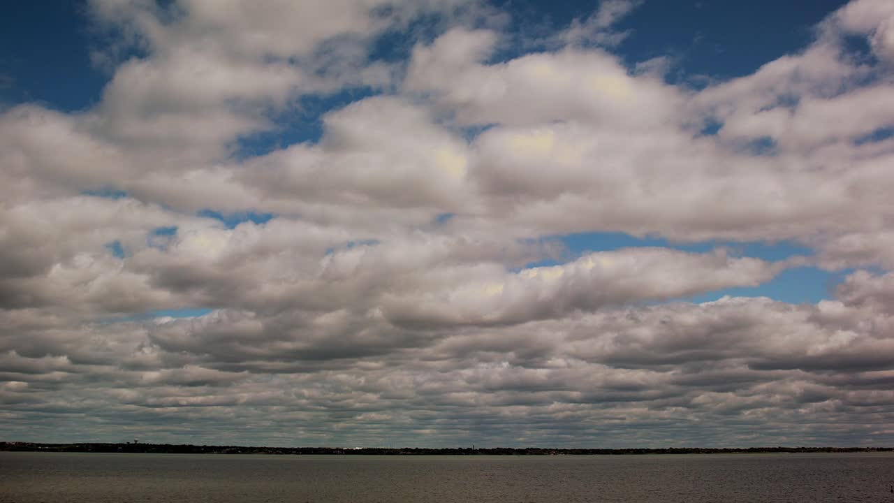 este es un video de las nubes moviéndose sobre un lago con barcos cruzando el agua