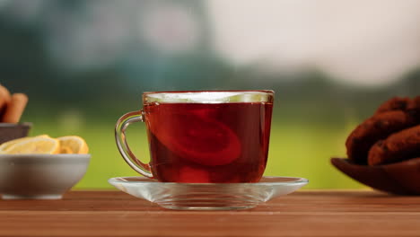 adding a lemon slice to a cup of hot tea