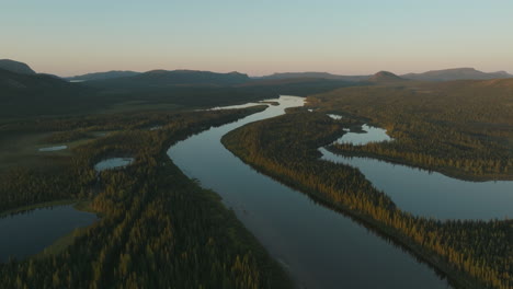 High-flying-sunset-drone-shot-looking-over-a-large-stream-in-the-Labrador-wilderness