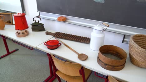 display of vintage kitchen tools on a classroom table with a chalkboard backdrop