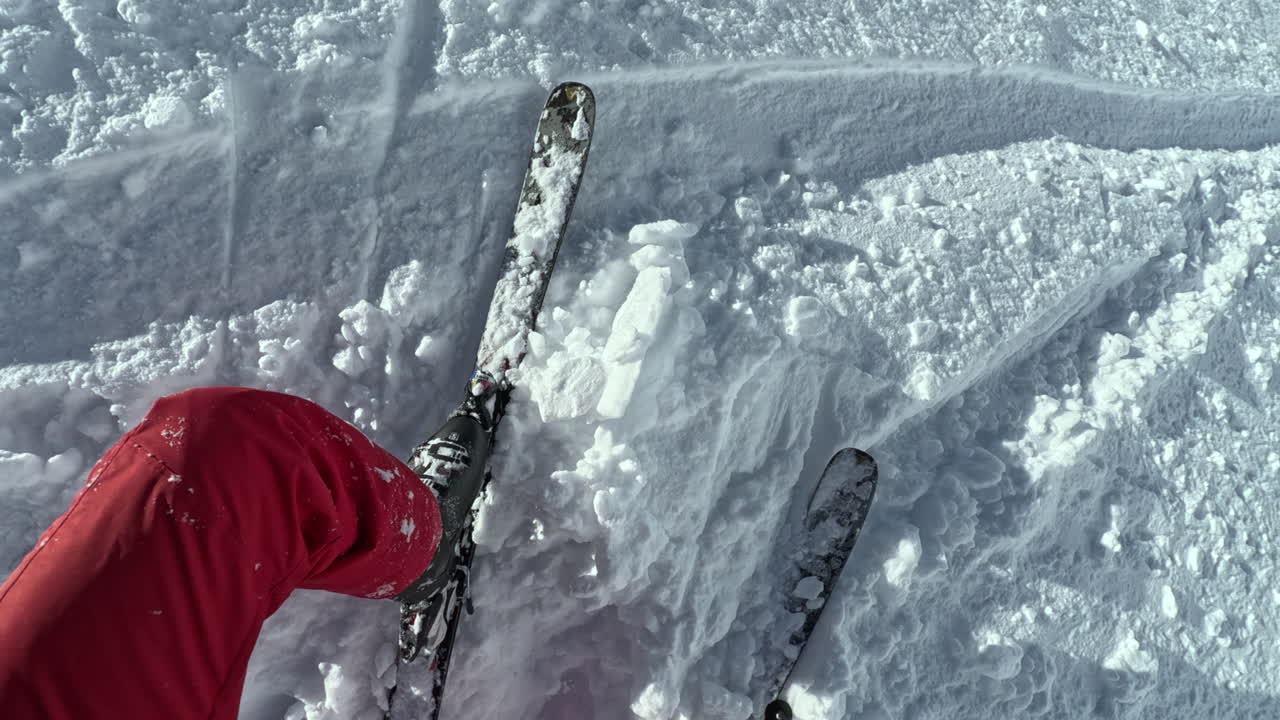 POV of skier cleaning boot of snow and putting ski back on after fall