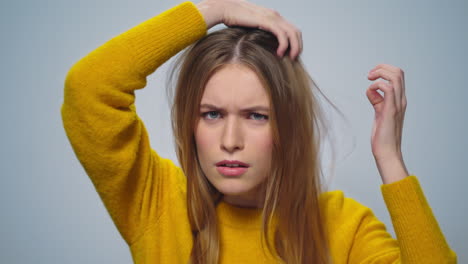 portrait of focused attractive woman improving appearance on grey background