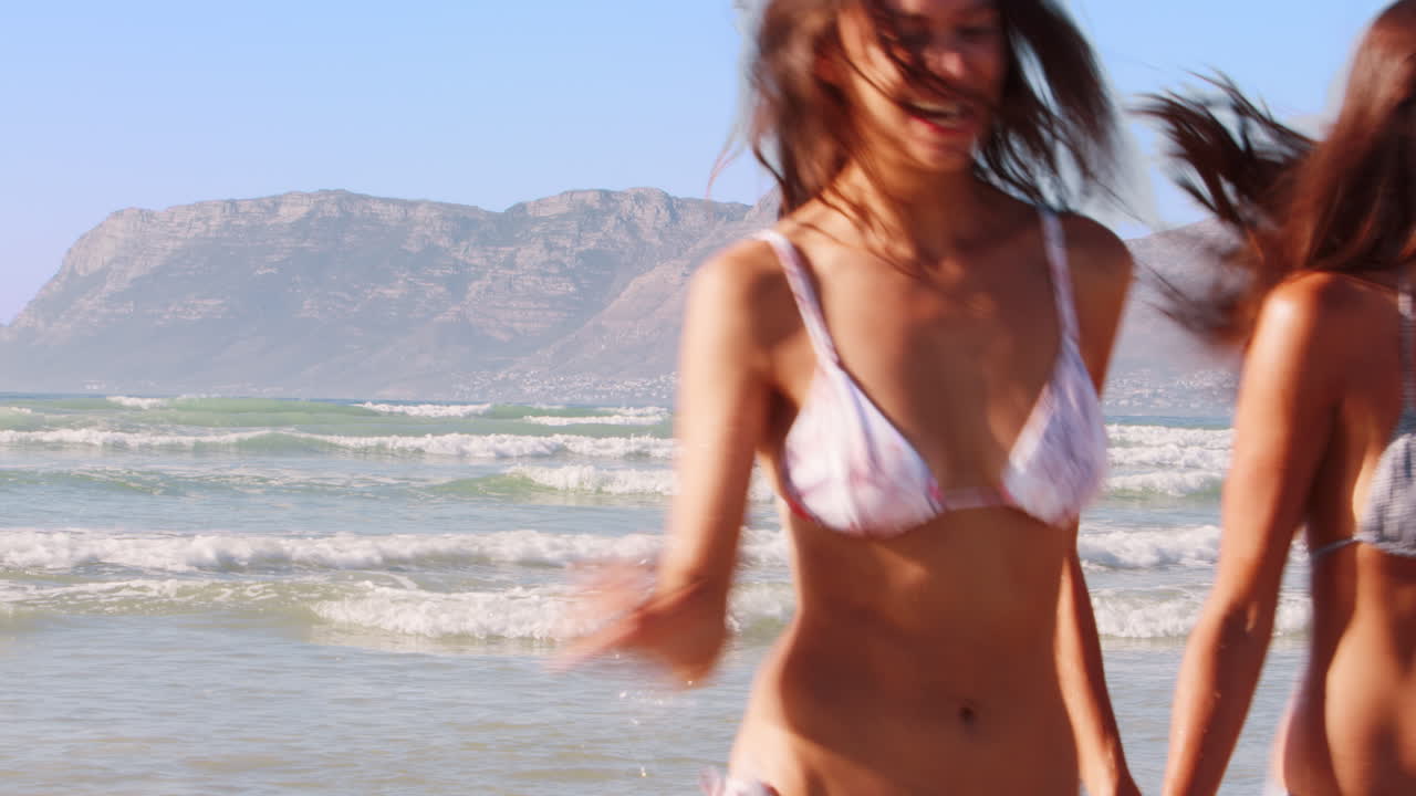 Amiche si divertono correndo tra le onde in vacanza al mare