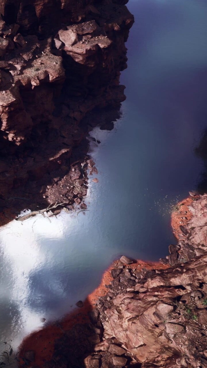 L'acqua scorre tra le rocce in uno stretto canyon sotto un cielo azzurro limpido.