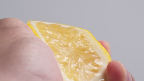 hand squeezes lemon juice on a white background, isolated