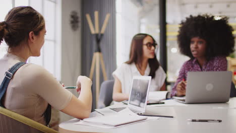 Young-female-creative-business-team-working-together-in-a-meeting-room,-close-up,-focus-on-foreground