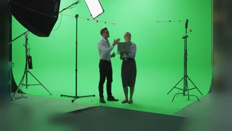 female and male colleagues wearing casual clothes talking, using laptop computer in green screen mock up chroma key studio. business, corporate office, work, technology concept.