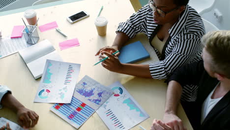 Top-View-Of-Businesswoman-In-Eyeglasses-And-Striped-Shirt-Is-Standing-Explaining-A-Project-To-Her-Colleagues-In-The-Office