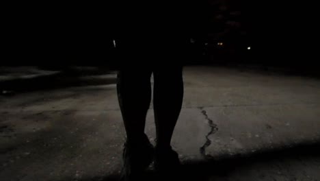 Low-angle,-dynamic-shot-of-a-person’s-feet-walking-down-the-street-in-the-middle-of-the-night-as-a-city-streetlight-has-short-circuited-and-is-flashing-ominously