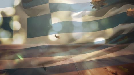 composición digital de grecia ondeando la bandera sobre las hojas de otoño que caen sobre la superficie de madera