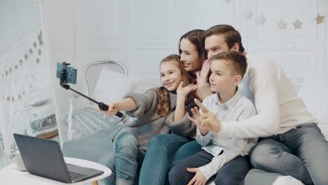 familia sonriente haciendo gesto de victoria frente al móvil en casa de lujo