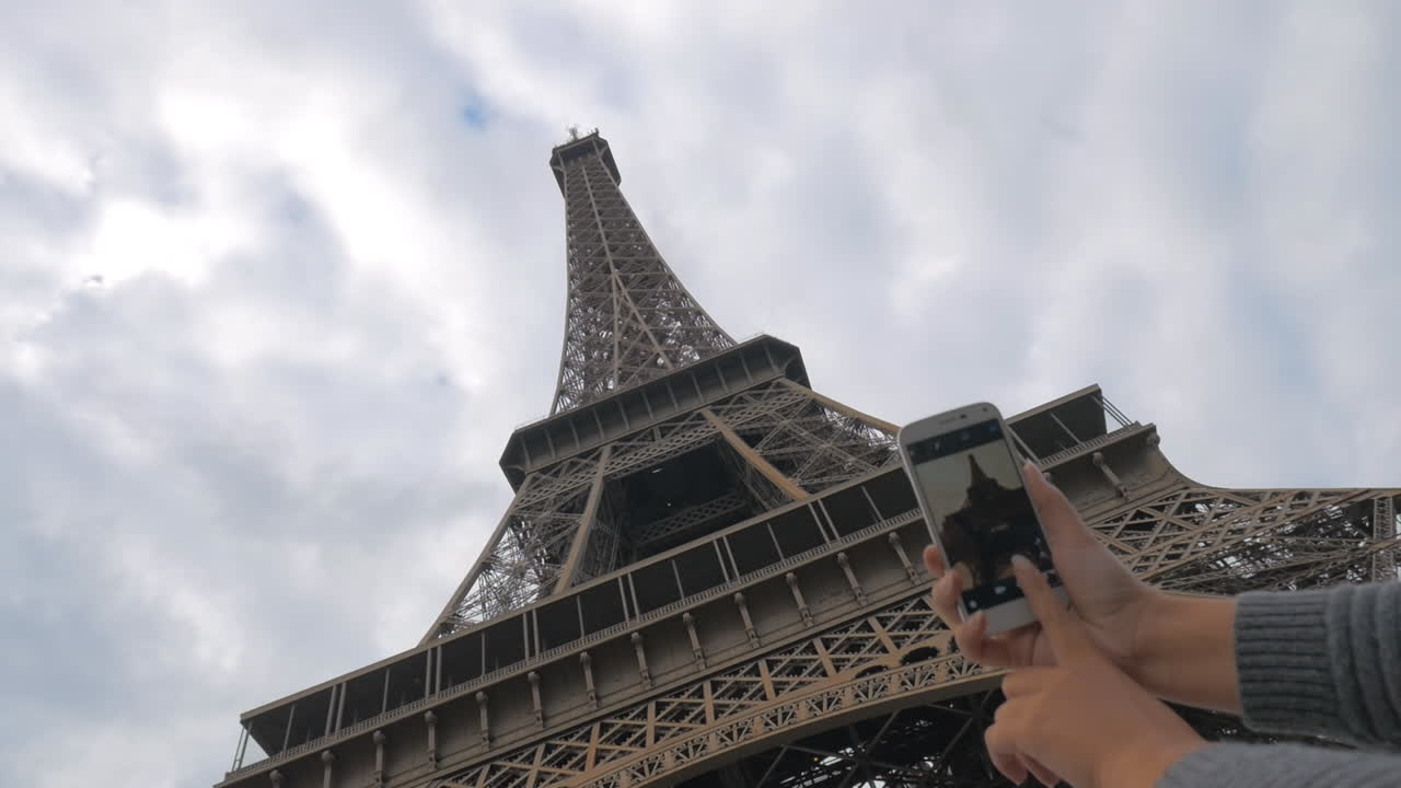 Woman with mobile taking picture of Eiffel Tower
