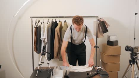 the man carefully packs the clothes in a cardboard box for return