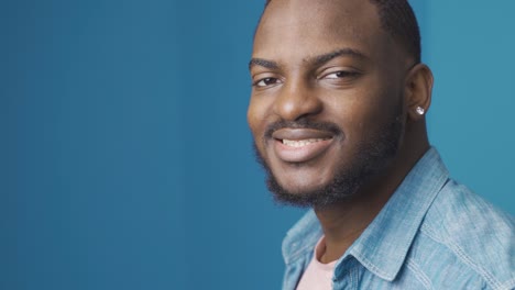 african young man turns and looks at camera. happy and positive.