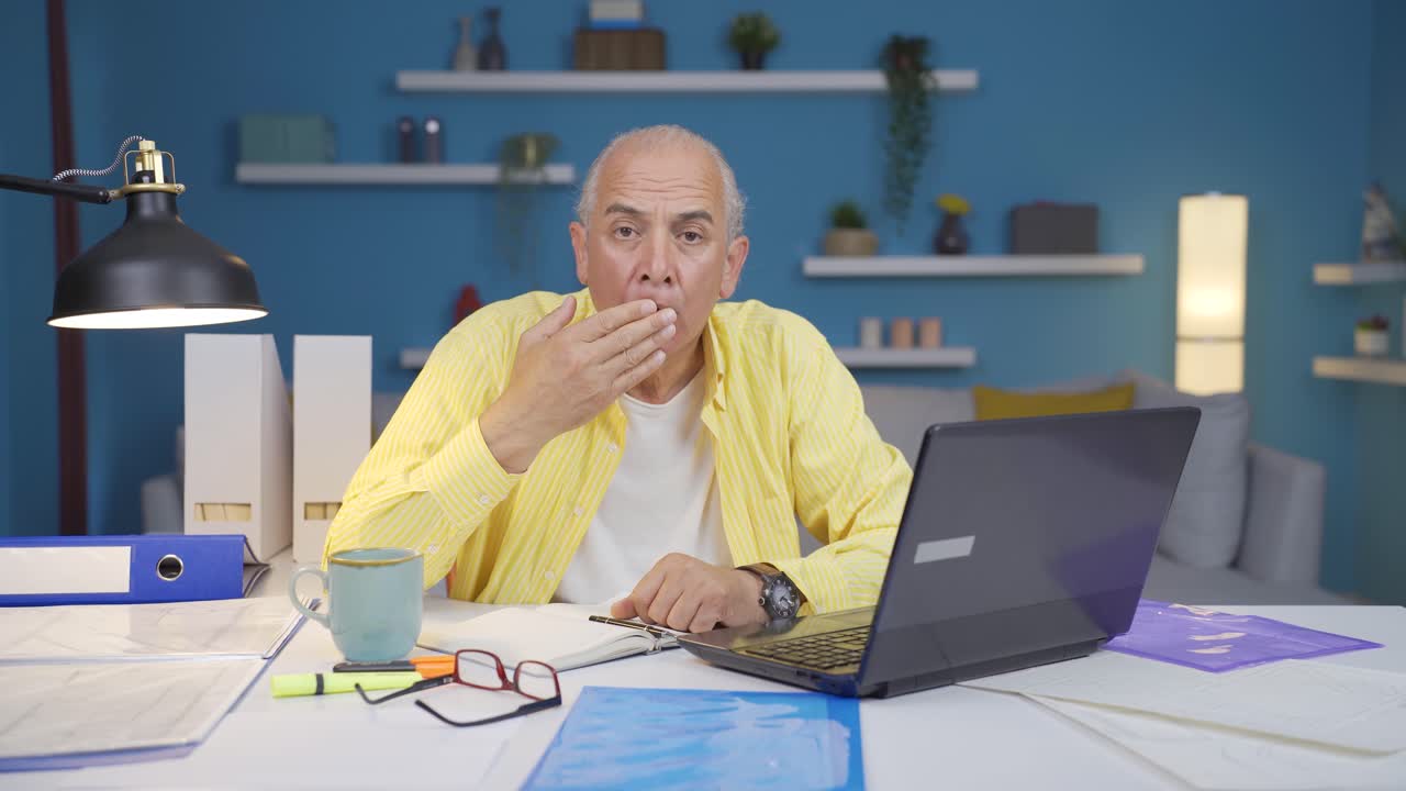 Home office worker old man looking at camera confused.