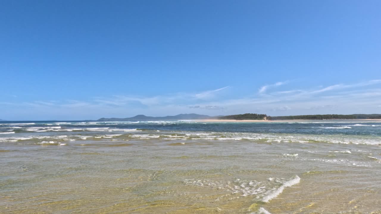 부드러운 파도가 모래 해변을 가로질러