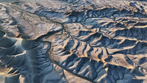 Natural-dry-riverbed-meanders-through-the-Utah-desert-mountain-valley,-drone