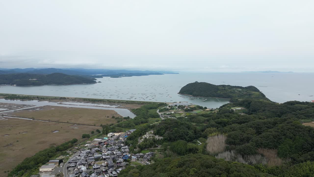 Slow drone flight over small coastal village in Japan next to ocean