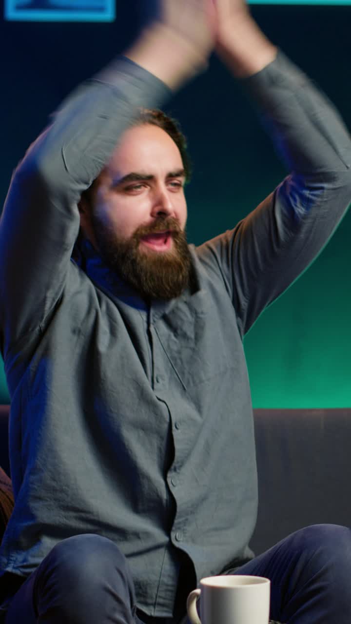 Vertical video Excited man at home enjoying football competition, clapping hands