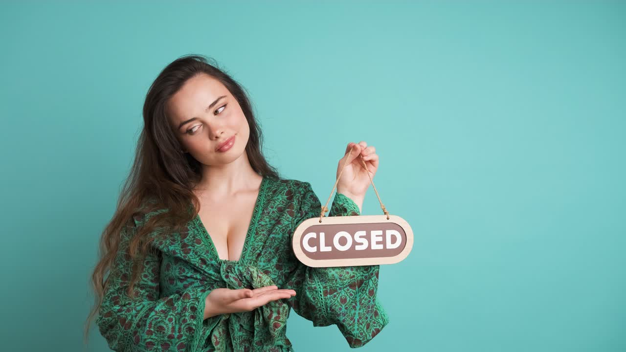 Upset young woman with closed sign in blue studio