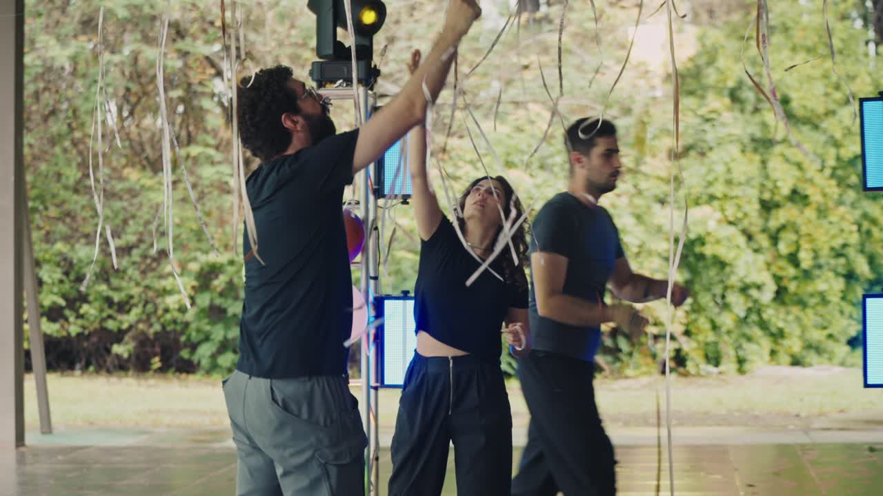 People decorating an outdoor event space with balloons and lights
