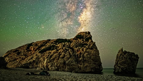 timelapse captures a man lying on the beach, gazing at the night sky beside a vast boulder