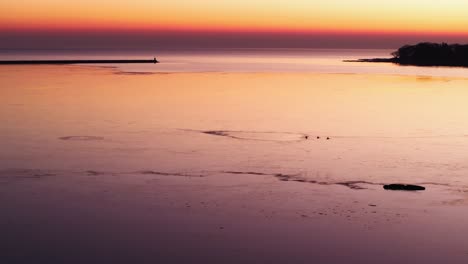 Sunset-glow-over-Port-Colborne-shores,-tranquil-water-reflecting-twilight-hues,-serene-evening