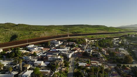 Aerial-view-rising-over-houses,-towards-the-border-wall-in-sunny-San-Ysidro,-Tijuana,-Mexico
