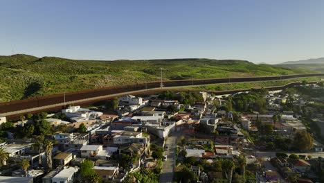 vista aérea que se eleva sobre las casas, hacia el muro fronterizo en el soleado san ysidro, tijuana, méxico