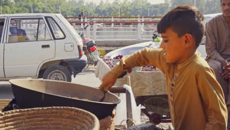 vibrant city square ambiance with a street child vendor skillfully grilling and selling fresh corn seeds on the cob from a popular street cart, close-up view, islamabad, pakistan.