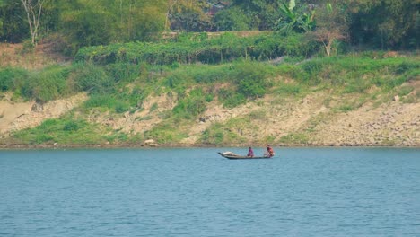 two asian fishermen paddle a traditional boat on a big river, enjoying the scenic beauty and tranquility of nature