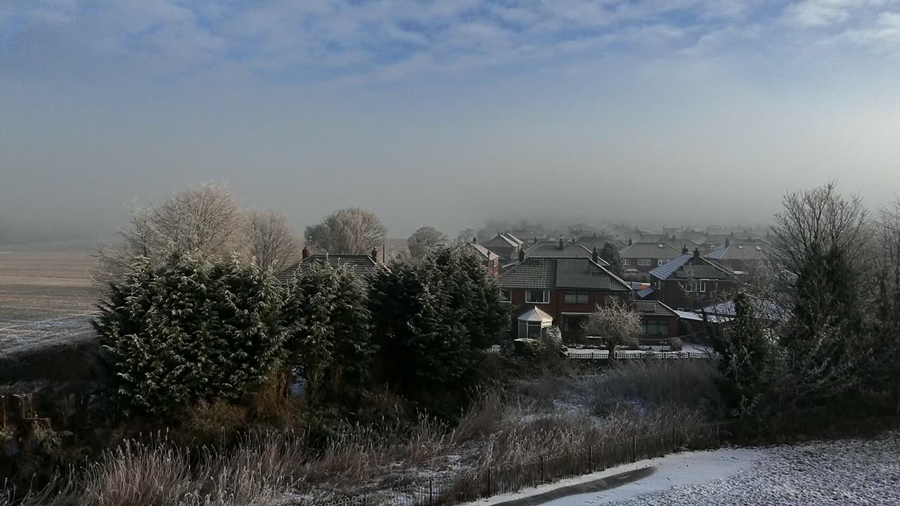 Aerial view over small town houses in England with frosty fog atmosphere on the horizon