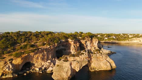 Aerial-View-Of-Rocky-Natural-Arch-Along-Palma-Coastline-During-Golden-Hour-Sunlight