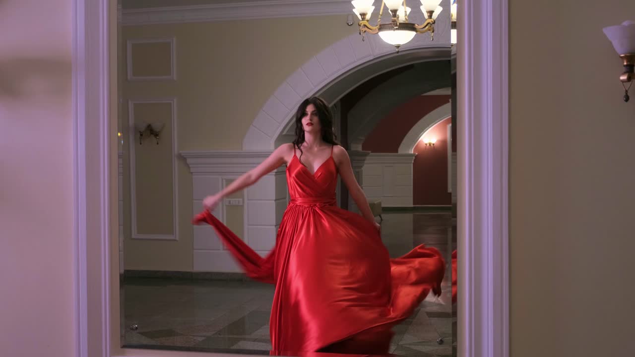 A Striking Display of Elegance: A Model Dances Gracefully in a Flowing Red Gown Within a Luxurious and Stylish Indoor Setting