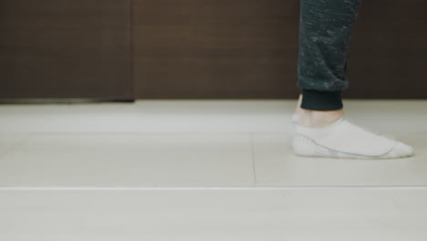 Closeup-man-feet-cleaning-floor-with-vacuum-cleaner.-Husband-hoovering-kitchen.