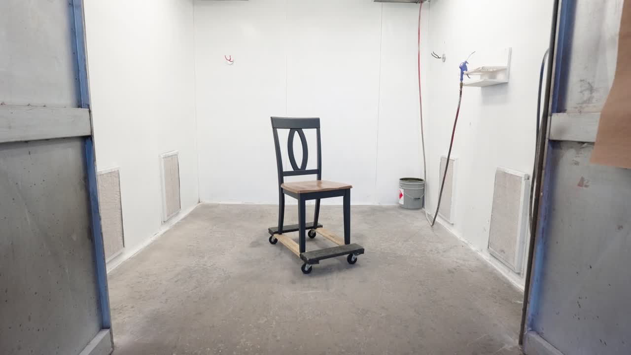 Camera dollies in on freshly painted dining chair in industrial spray booth