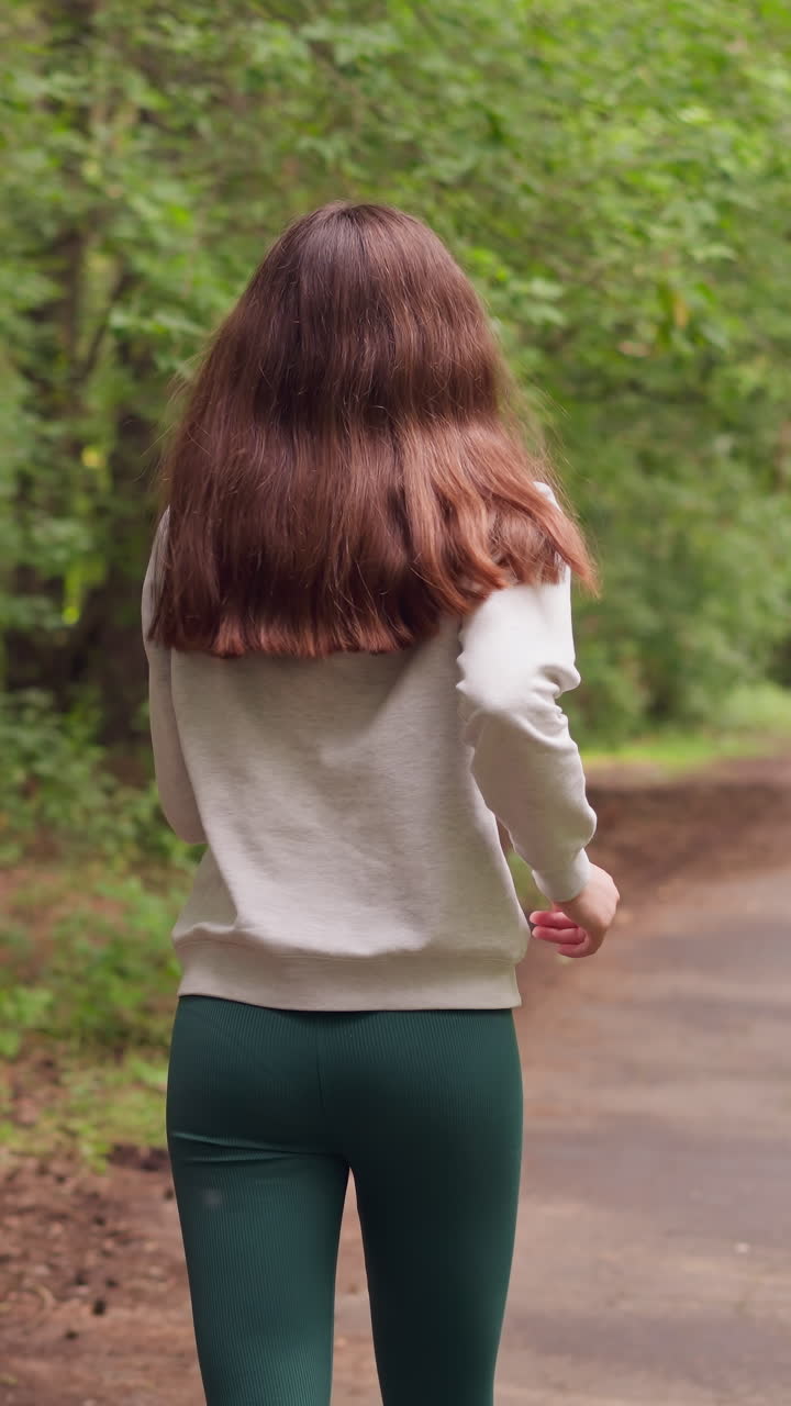 도시 공원에서 경로를 따라 조하는 여성, 다양한 종류의 나무로 둘러싸인 신선한 공기에서 체력 운동과 신체 건강을 개선하는 여성