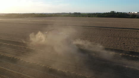 aerial view of combine, grain harvester in plain agricultural farming field harvesting wheat, drone shot