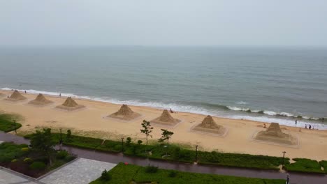 Aerial-cityscape-of-Nanhai-China,-drone-reveals-scenic-artistic-sand-sculpture-on-the-beach-and-modern-skyline-of-the-Chinese-city-with-air-pollution