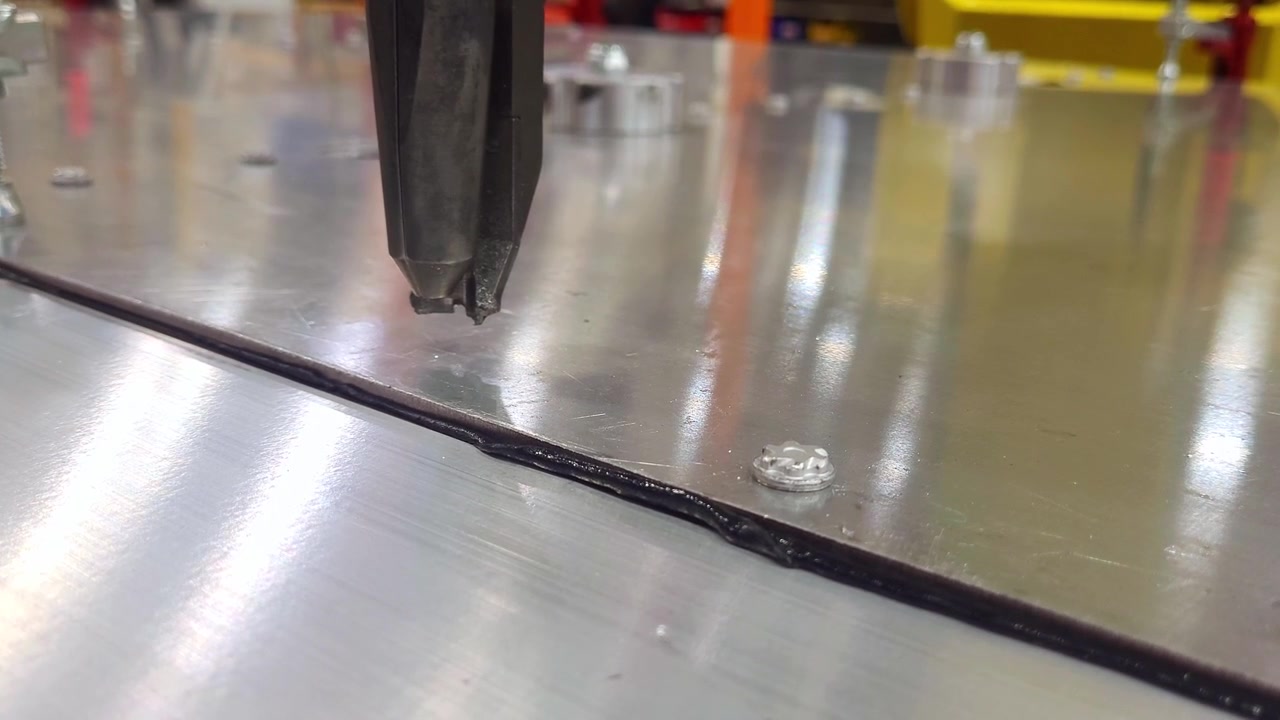 Robotic arm fixing two metal sheets with self piercing rivet in closeup