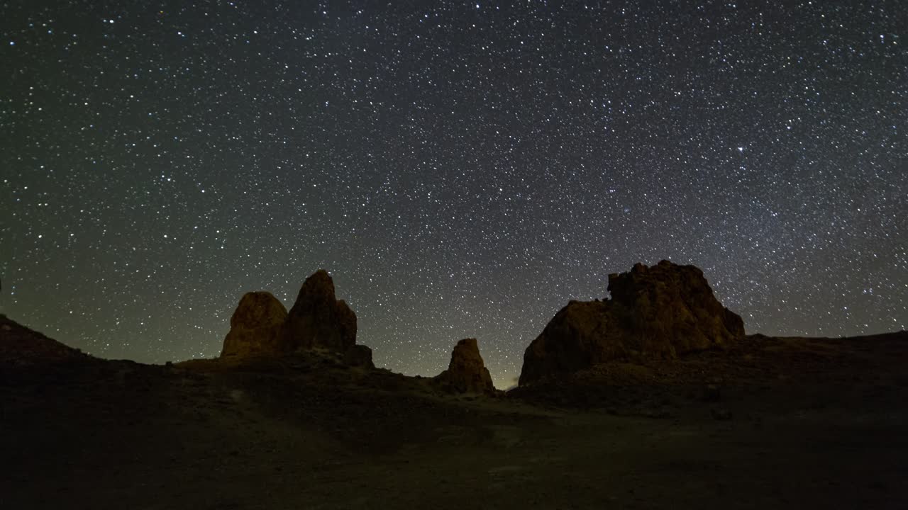 Panning motion time lapse of the milky way, stars and clouds over the rock spires of Trona Pinnacles